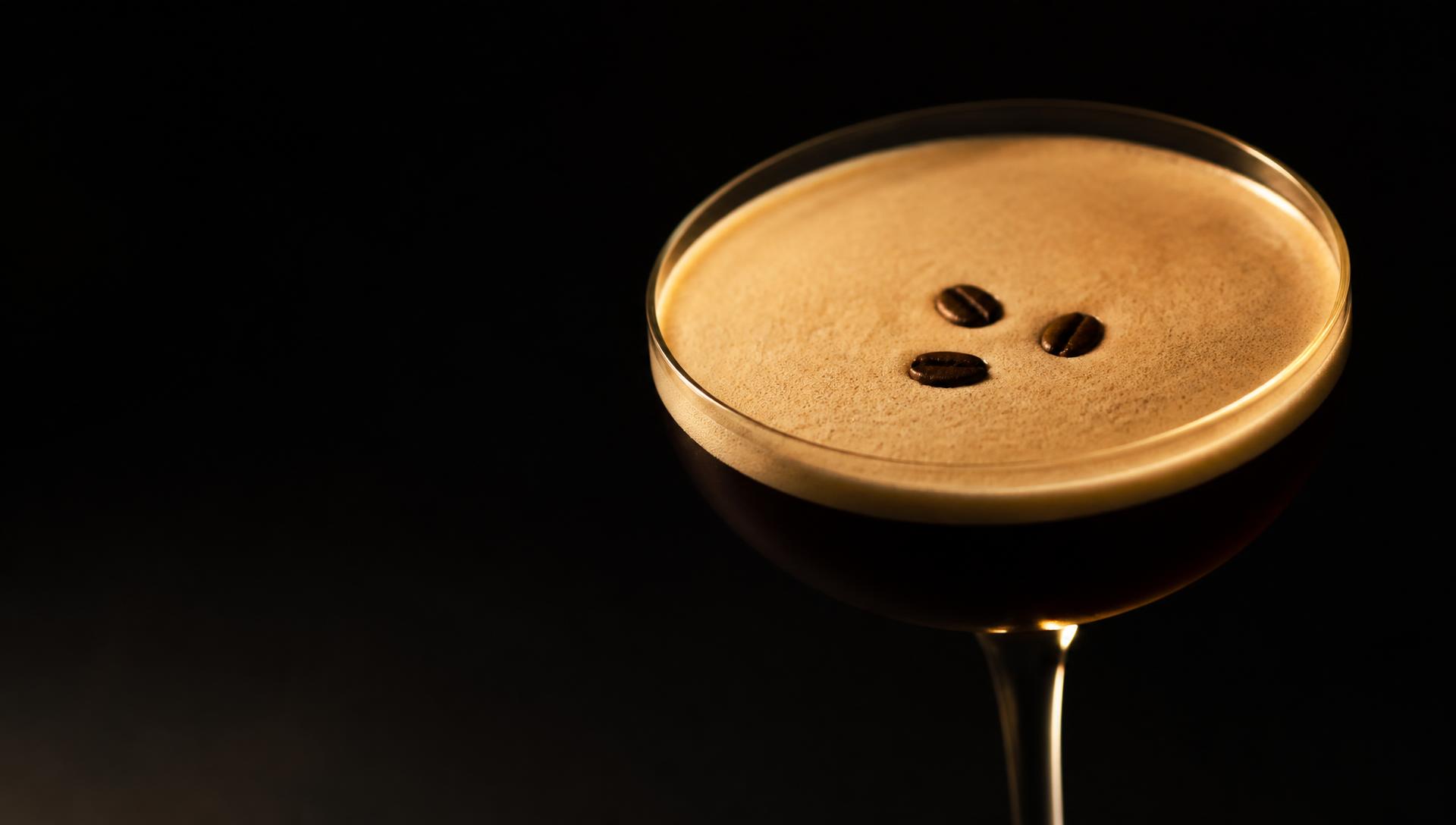 A freshly poured espresso martini lit with warm gold light